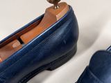 pair of blue leather shoes with a wooden heel on a white surface