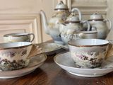 two cups and saucers on a table with a teapot