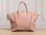 un sac à main en cuir rose posé sur une table en bois