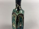 a small blue and green vase sitting on a white surface
