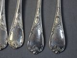 four silver spoons are lined up on a black surface