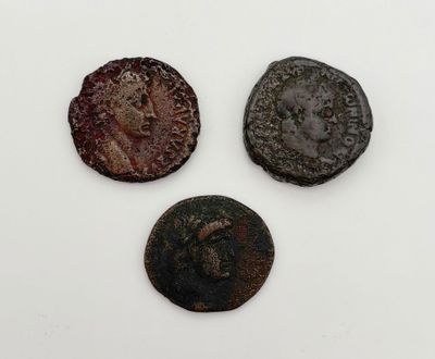 trois pièces romaines, dont l'une représente une tête et l'autre un visage
