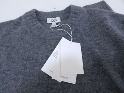 un pull gris avec une étiquette, posé sur une table blanche