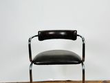 une chaise en cuir noir et chrome posée sur un parquet