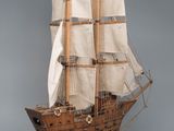 wooden model of a sailing ship on a stand on a gray background