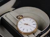 une montre de poche en or posée dans un écrin sur une table