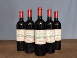 four bottles of red wine are lined up on a table