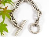 a silver bracelet with a cross on it next to a plant