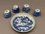 une assiette bleue et blanche sur laquelle sont posés quatre salières et poivrières