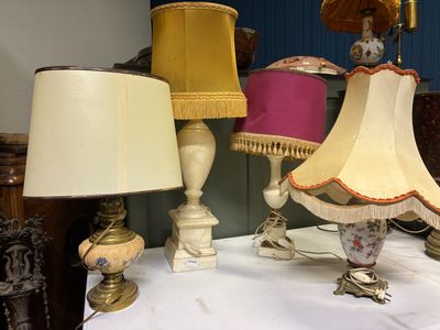 de nombreuses lampes posées sur une table recouverte d'une nappe blanche