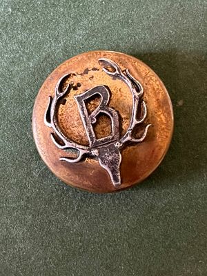 une image représentant un bouton en métal orné d'une tête de cerf