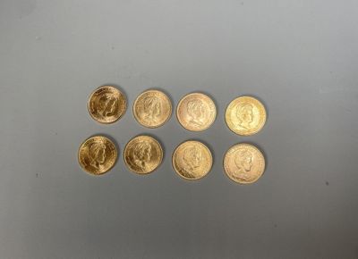 six pièces d'or sont disposées en ligne sur une surface grise
