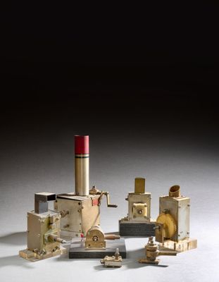 une petite maquette d'usine d'où sort un tuyau rouge sur le côté