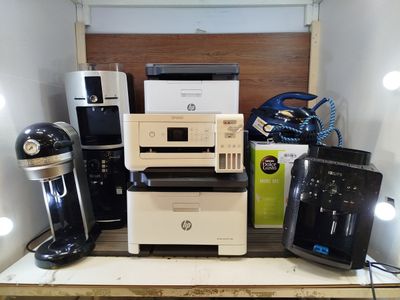 de nombreux modèles différents d'imprimantes et de machines à café sur une étagère