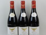 trois bouteilles de vin rouge sont alignées sur une surface blanche