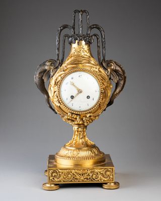 une horloge en or posée sur un socle, surmontée d'un oiseau