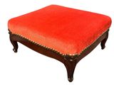 an orange ottoman with a wooden frame and studding on the legs