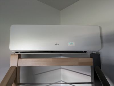 un climatiseur blanc posé sur une étagère en bois