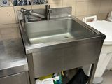 un évier en acier inoxydable dans le coin d'une toilette publique