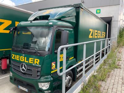 a green truck that is parked next to a building