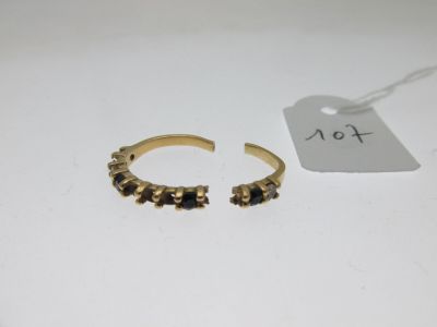 une paire de bagues en or ornées de pierres noires, posées sur une table blanche