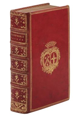 un vieux livre à la couverture rouge ornée d'un emblème doré
