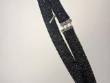 un gros plan d'un bracelet en perles noires posé sur une surface blanche