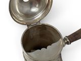 a silver cup with a wooden handle on a white surface