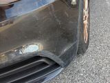 a close up of a car ' s front bumper with a cat sticking out of it