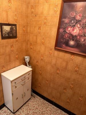 a small bathroom with a sink, toilet and a painting on the wall