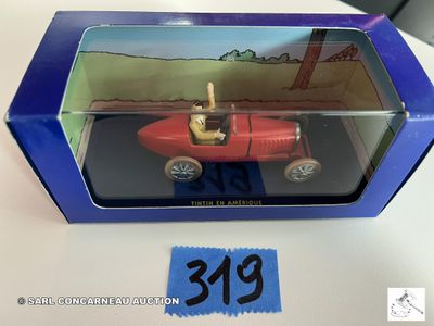 une petite voiture rouge dans une boîte bleue posée sur une table