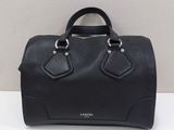 a black handbag sitting on top of a table next to a wall