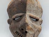 an old wooden mask on a white surface with a white background