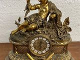 a gold clock sitting on top of a wooden table