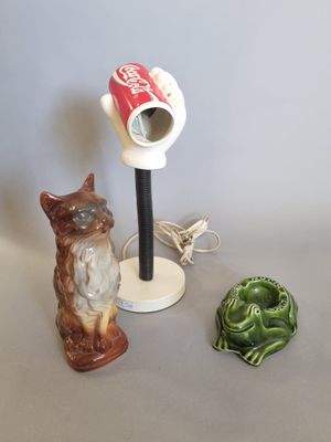 une lampe posée sur une table, à côté d'un chat et d'une figurine de grenouille