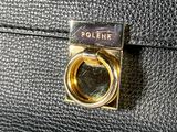 a close up of a black purse with a gold ring on it