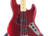 a close up of a red electric bass guitar on a stand