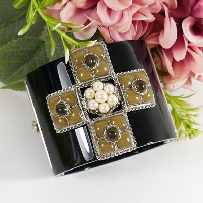 black and white cuff bracelet with pearls and flowers on a white surface