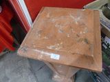 a small table with a brown top sitting on a sidewalk