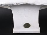 a white vase with a coin on top of it