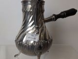 a silver coffee pot with a handle on a glass table
