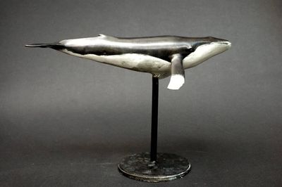 sculpture d'une baleine à bosse posée sur un socle, sur fond gris