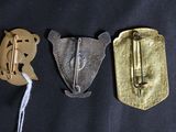 three different types of metal brooches on a black surface