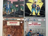 four books of french comics on a white surface