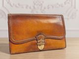 a brown leather purse sitting on top of a wooden table