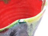 a close up of a red and green vase on a white surface