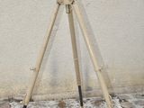 a wooden tripod on a stone floor next to a white wall