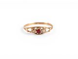 un gros plan d'une bague en or sertie d'une pierre rouge et blanche