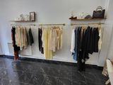 a photo of a clothing store with clothes hanging on a rack