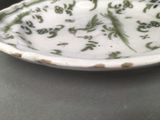 a white plate with green designs on it sitting on a table